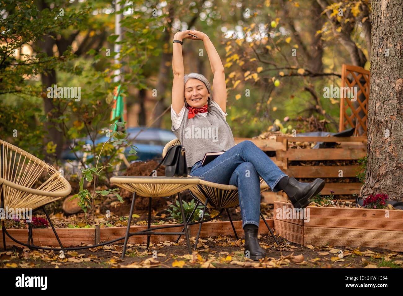 Une femme qui a l'air bien assise sur le banc dans le parc et qui a l'air détendue Banque D'Images