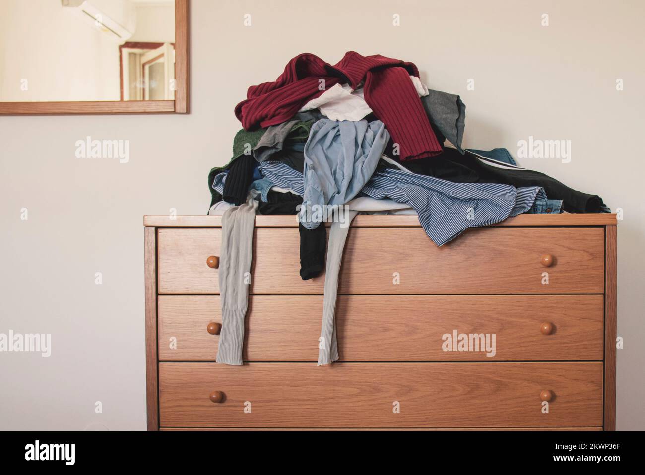 Pile de vêtements dépliés sur un pour le linge sur un tiroir. Concept de minimalisme, de mess et de nettoyage de garde-robe. Banque D'Images