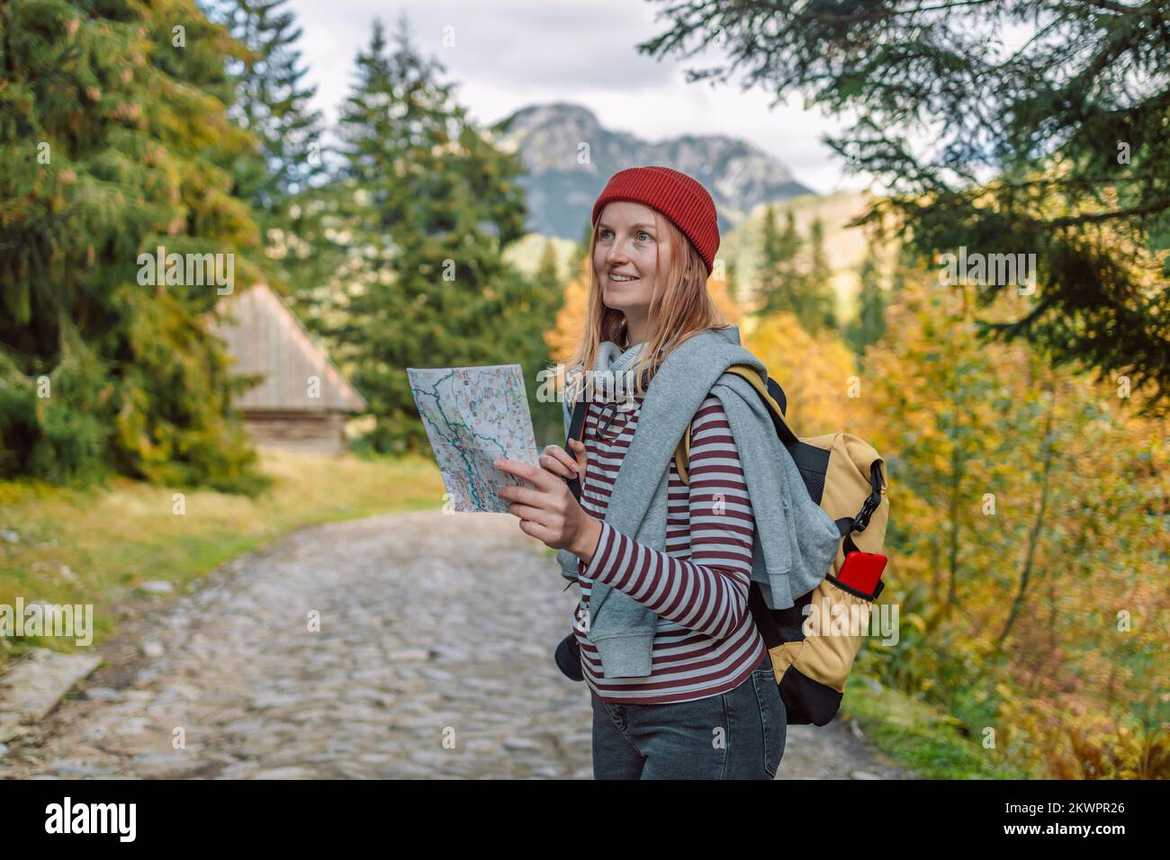 Femme randonneur, cherchant la bonne direction sur la carte tout en faisant une pause de randonnée, s'amuser et se détendre tout en passant une journée d'automne à l'extérieur. Banque D'Images