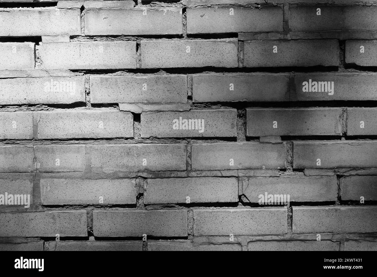 Un mur de briques classique et commun aux murs abîmés et usés dans un monochrome noir et blanc. Banque D'Images