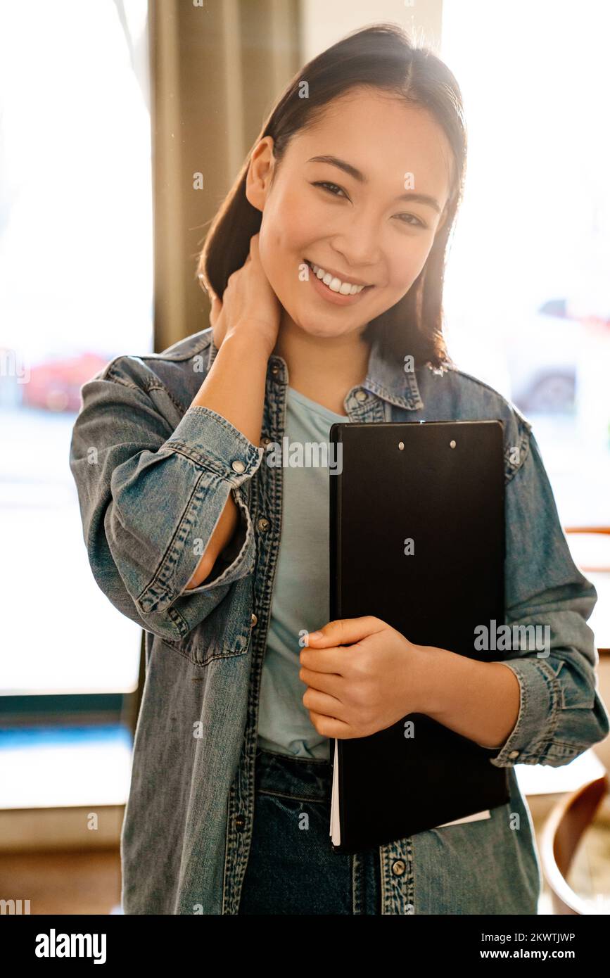 Une jeune serveuse asiatique souriait alors qu'elle travaillait au café Banque D'Images