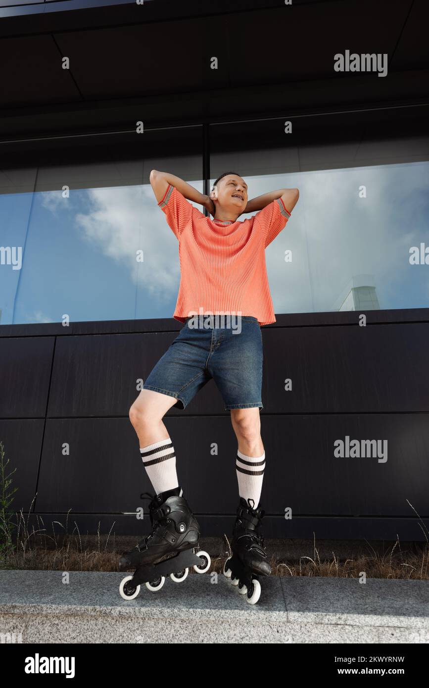 Vue à angle bas de l'homme gai dans les lames de rouleau regardant loin sur la rue urbaine, image de stock Banque D'Images