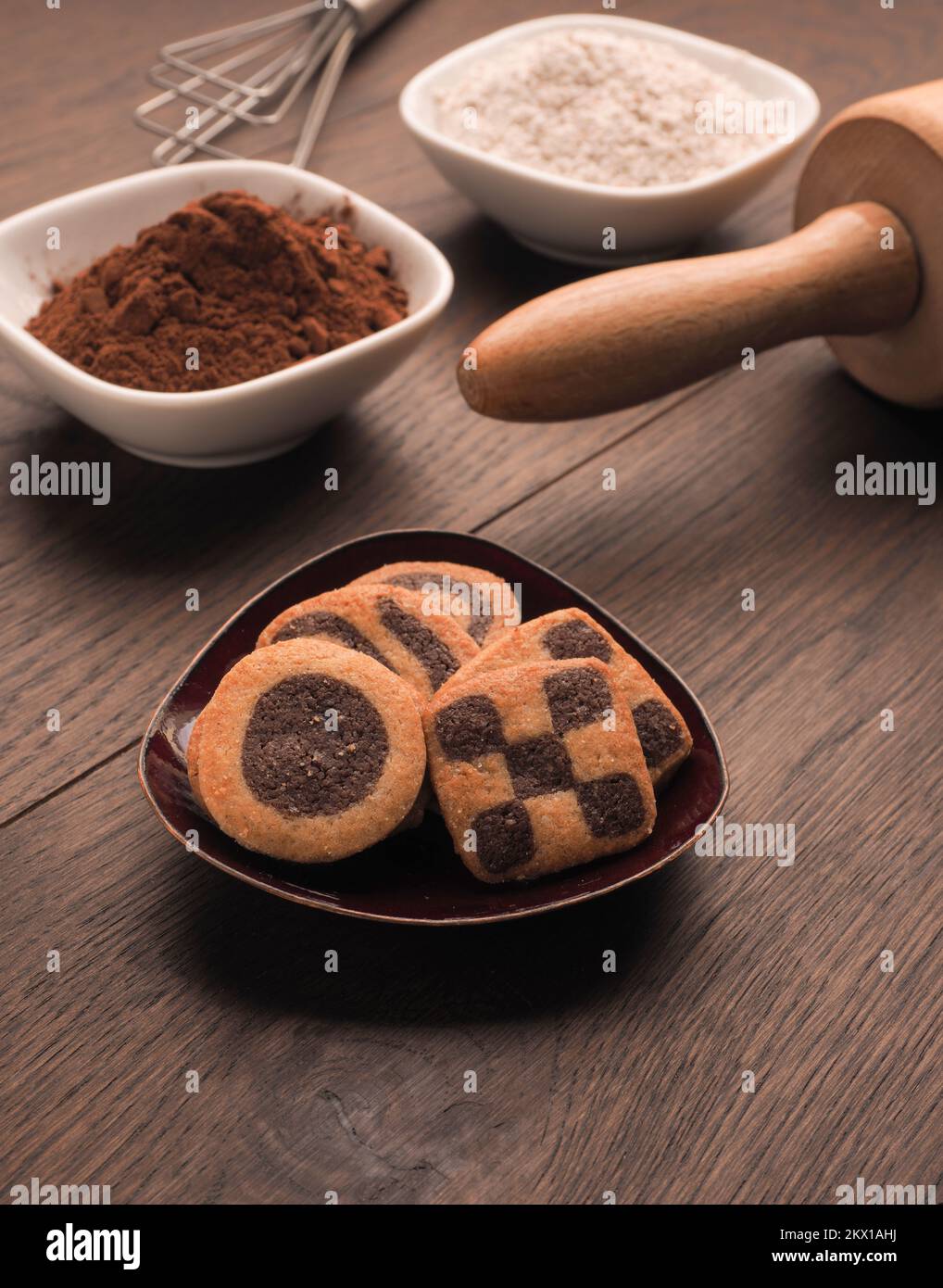 Biscuits noirs et blancs sur une table de cuisine en bois avec des ustensiles de cuisine Banque D'Images