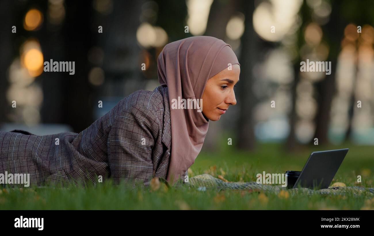Amicale islamique d'affaires femme musulmane fille dans hijab pelouse allongée dans le parc en plein air femme enseignant en ligne mentor faire appel vidéo chat conférence Banque D'Images