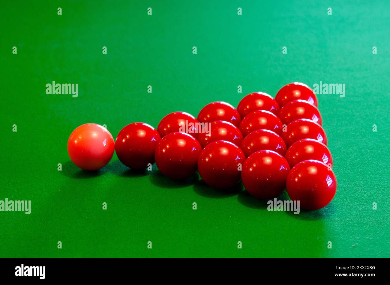 Boules de billard rouges et roses disposées pour jouer sur une table de billard verte baiser Banque D'Images