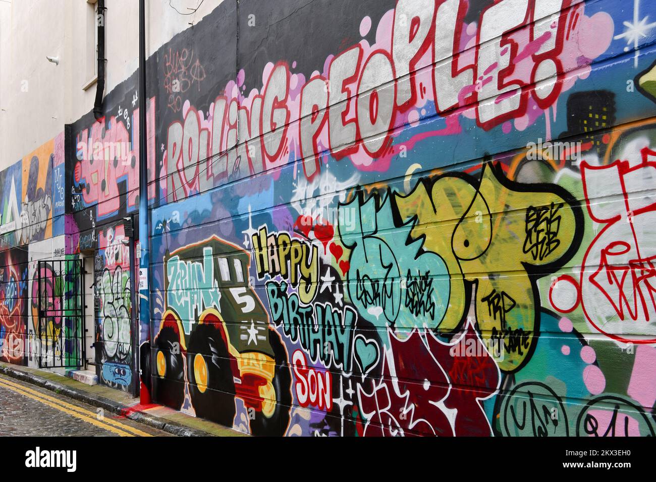 Un mur dans la rue Grimsby, Shoreditch couvert de graffitis comprenant un camion et les mots roulant personnes et heureux anniversaire de fils Banque D'Images
