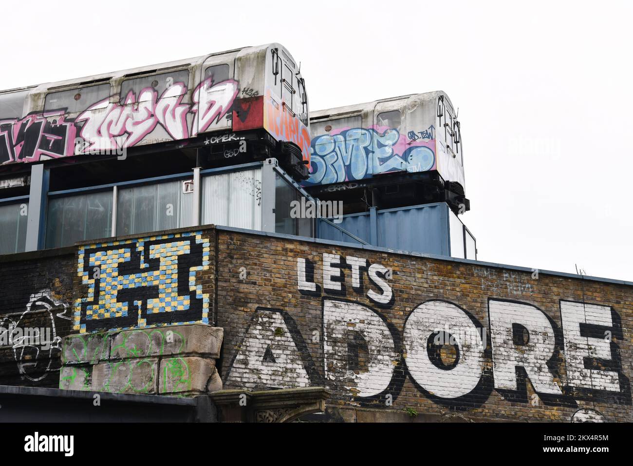 Deux trains de métro avec graffiti et mots Icarus et Ikar au sommet d'un bâtiment sur Great Eastern Street à Shoreditch Londres Banque D'Images