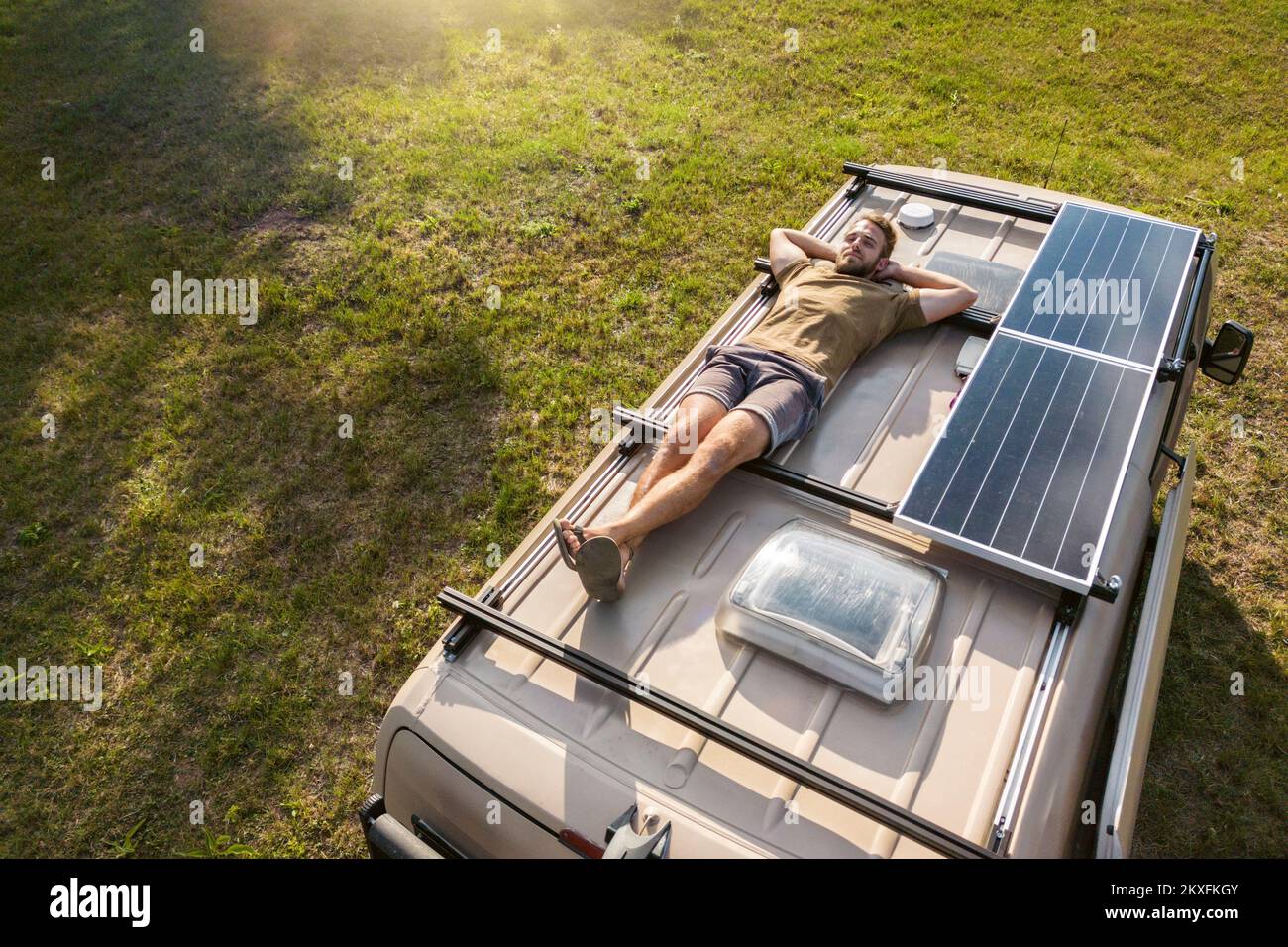 Homme se reposant sur le toit d'une camionnette de camping Banque D'Images
