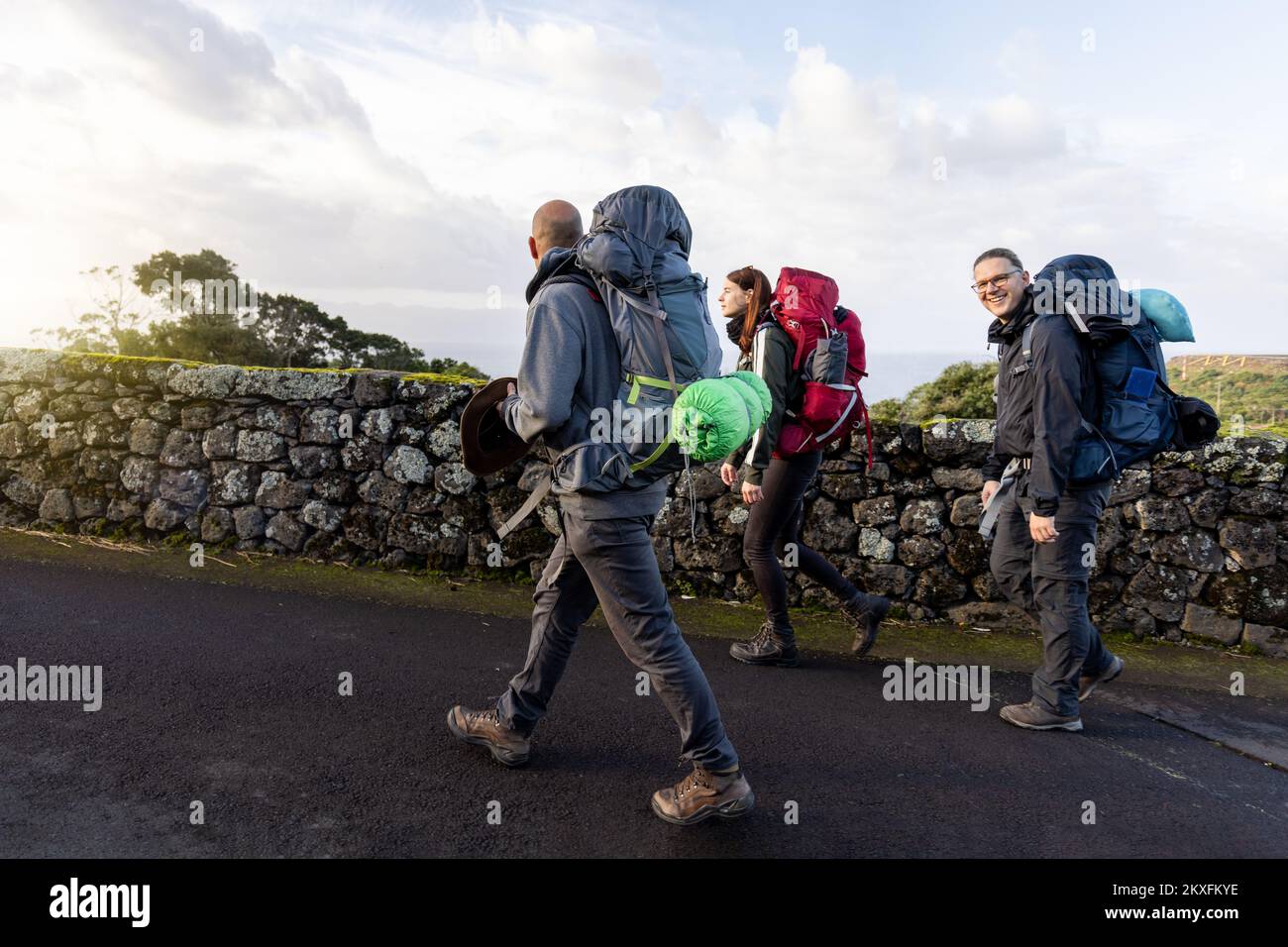 Groupe d'amis randonnée avec de grands sacs à dos sur une route dans les Açores Banque D'Images