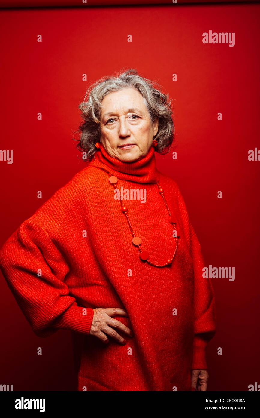 Femme âgée portant des vêtements rouges sur fond rouge Banque D'Images Femme âgée portant des vêtements rouges sur fond rouge Banque D'Images