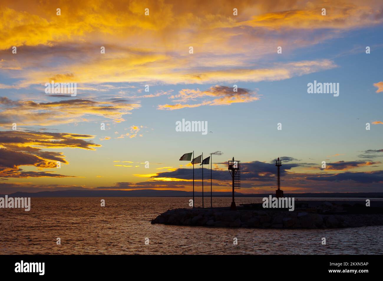 Lever du soleil dans le port de Termoli, vous pouvez voir la silhouette des phares et des drapeaux soufflant dans le vent - Molise, Mer Adriatique Banque D'Images