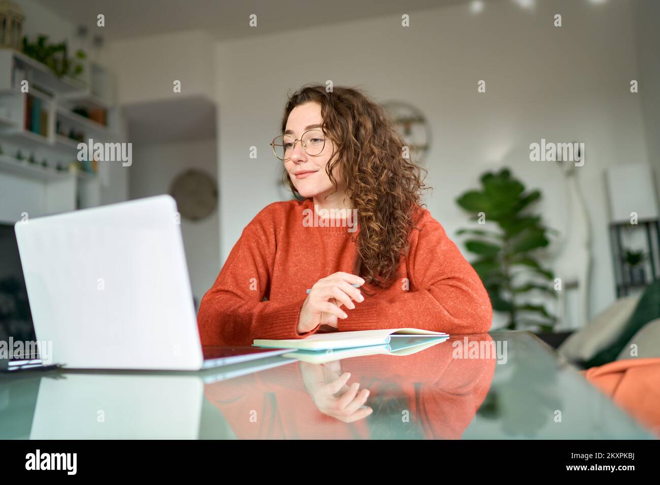 Jeune étudiante utilisant un ordinateur portable regardant des webinars en ligne écrivant à la maison. Banque D'Images