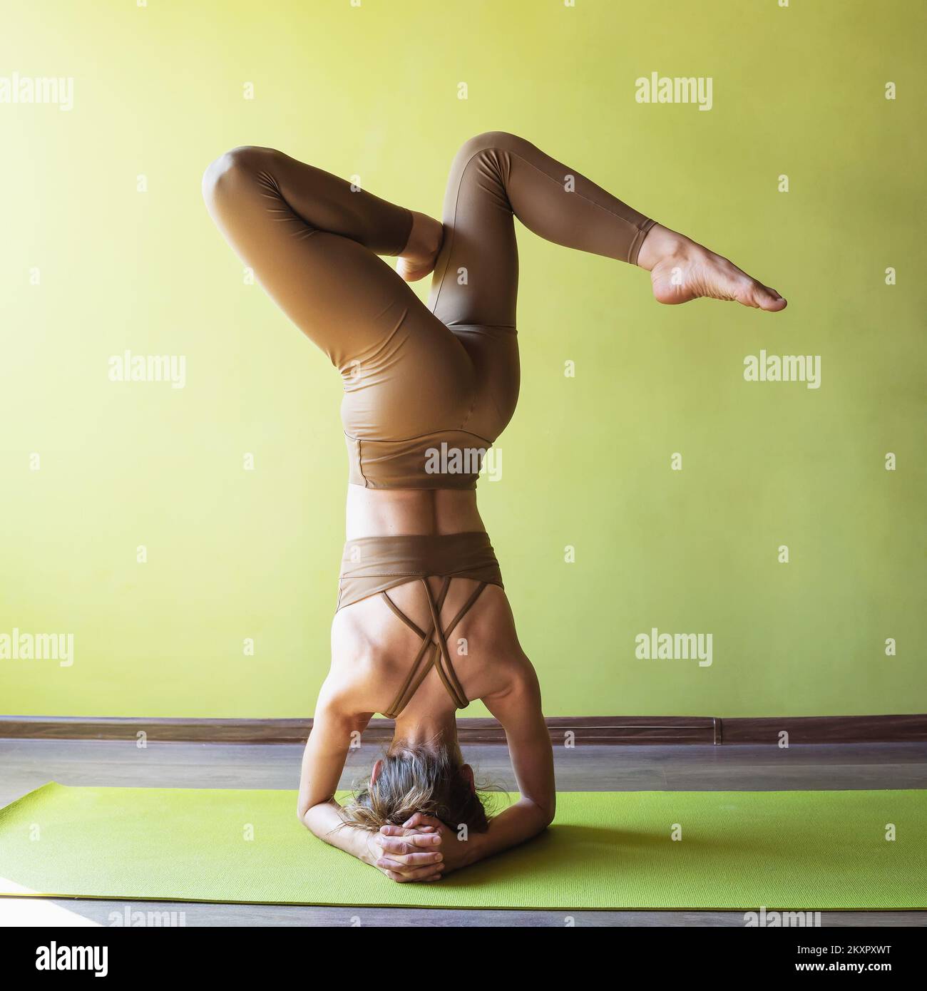Une femme pratiquant le yoga, exécute une variante de l'exercice shirshasana avec une jambe courbée, l'asana inversé, s'entraîne en se tenant sur ses avant-bras dans le Banque D'Images