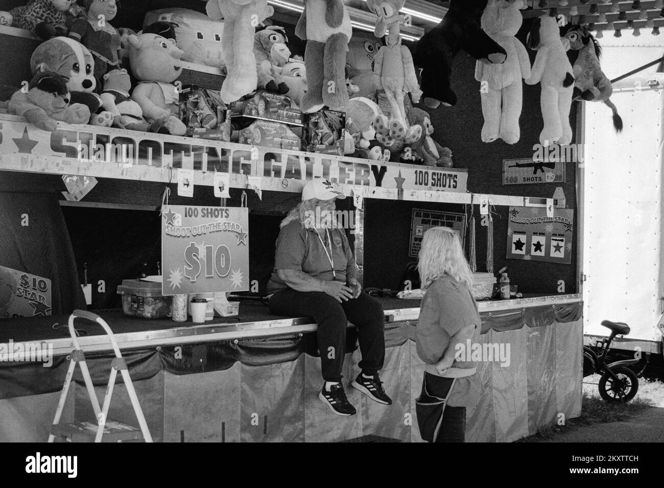 Deux ouvriers du carnaval discutant dans une galerie de tir à la Hopkinton Fair. Hopkinton, New Hampshire. L'image a été capturée en noir et blanc analogique f Banque D'Images