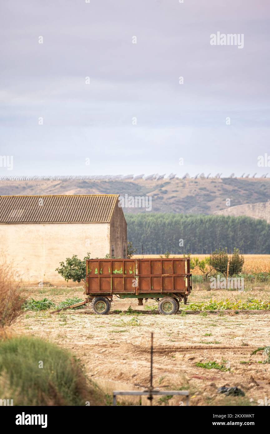 Image rurale d'une remorque-tracteur utilisée dans l'agriculture garée dans un champ de ferme près d'un hangar Banque D'Images