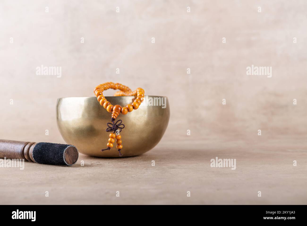 Bol de chant tibétain avec bâton, perles de mala torons utilisés pendant les mantra méditations sur fond de pierre beige. Instruments de musique pour medi Banque D'Images