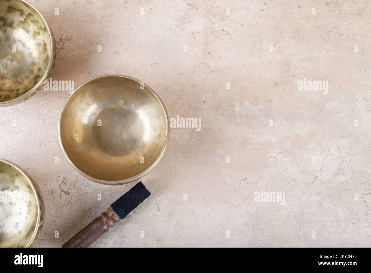 Bols de chant tibétains avec bâton utilisé pendant mantra méditations sur fond de pierre beige, vue de dessus, plat. Instruments de musique pour la guérison du son pour les médicaments Banque D'Images