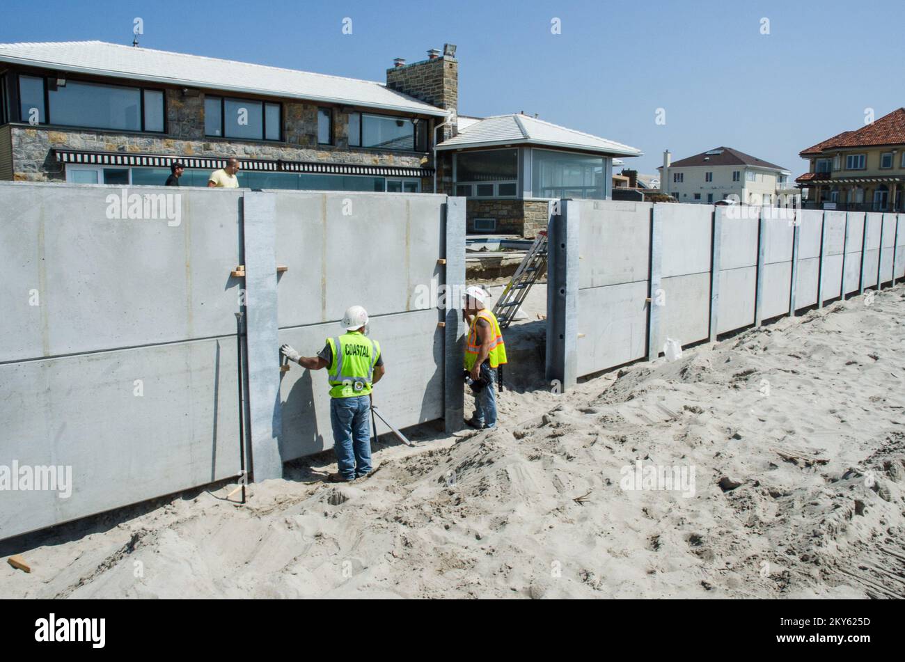 Belle Harbour, N.Y., 21 mai 2013 le département des parcs de la ville de New York, avec un financement partiel du programme d'aide publique de la FEMA, construit un mur-chicane dans les Rockaways, de la rue Beach 126th à la rue Beach 149th, pour remplacer l'ancien mur endommagé pendant l'ouragan Sandy. Les travailleurs placent une section de béton dans les pilages en « H » d'acier qui ont été conduits à une profondeur de 25 pieds. Le mur du déflecteur se trouve à quatre pieds au-dessus du niveau de la rue. K.C.WILSEY/FEMA. New York ouragan Sandy. Photographies relatives aux programmes, aux activités et aux fonctionnaires de gestion des catastrophes et des situations d'urgence Banque D'Images