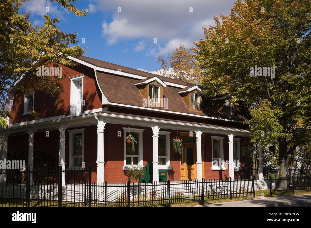 Ancienne maison restaurée de 1870 entourée d'une clôture en fer forgé noir en automne. Banque D'Images