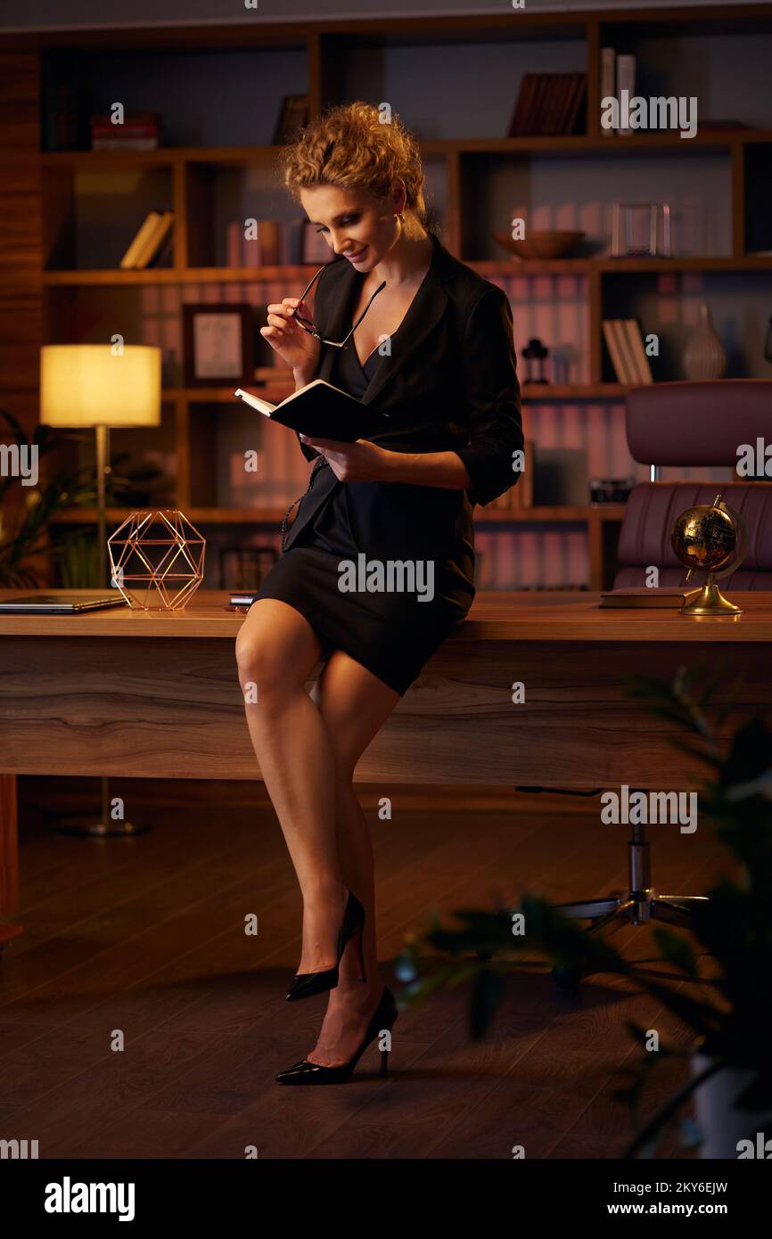 Jeune femme d'affaires déterminée, entrepreneur professionnel, lit un livre. Femme d'affaires dans un beau bureau à la lumière du cinéma. Un beau Banque D'Images