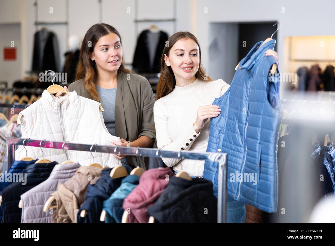 Les jeunes femmes joyeuses choisissent entre les gilets blancs et bleus  dans un magasin de vêtements Photo Stock - Alamy
