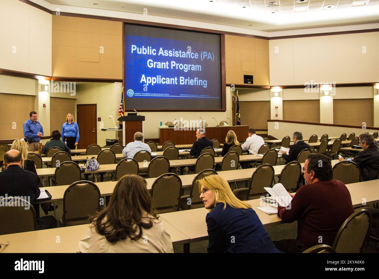 Canton de Clinton, MI, 9 octobre 2014 - Samuel Jonker-Burke (à gauche, arrière-plan, debout), coordonnateur de l'UASI de la police de l'État du Michigan et spécialiste des subventions, et Brianna Briggs (à droite, arrière-plan, debout), police de l'État du Michigan, analyste de département, S'adresser aux participants à une réunion d'information des demandeurs d'aide publique de la FEMA au district scolaire intermédiaire de Macomb, dans le canton de Clinton, Michigan, en réponse à de graves tempêtes et inondations sur 11-13 août 2014 qui ont eu des répercussions négatives sur les comtés de Wayne, Oakland et Macomb, au Michigan. La FEMA soutient les gouvernements locaux et étatiques et les entités tribales dans leur ef Banque D'Images