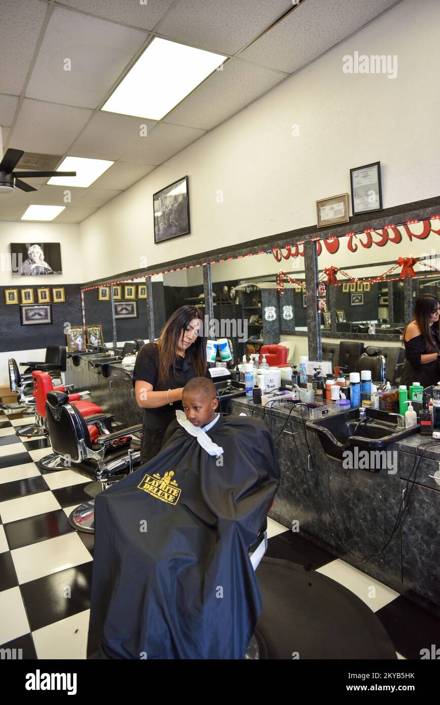 Femme Barber et coiffeur coupant les cheveux d'un jeune garçon noir Banque D'Images