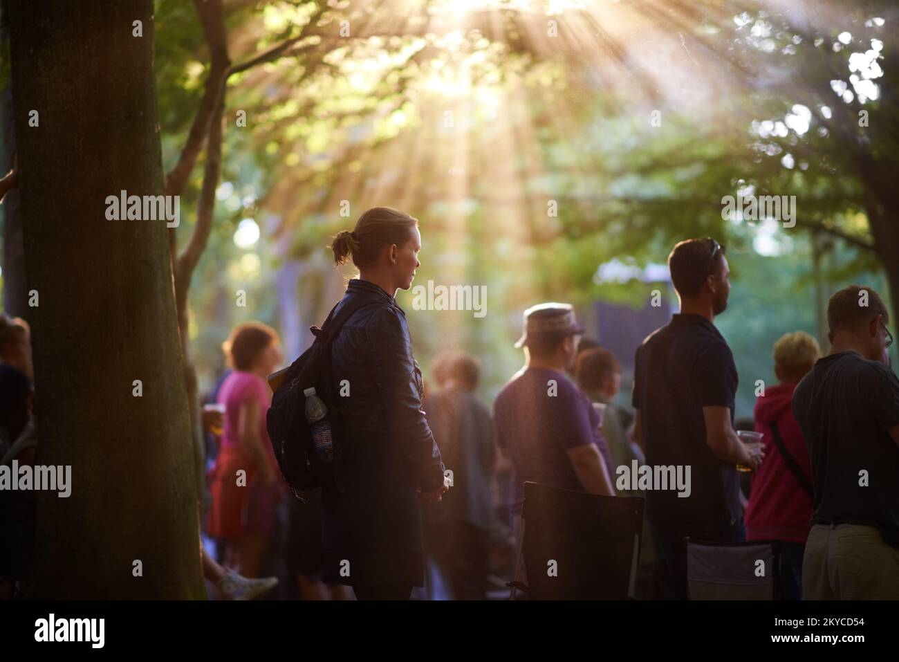 Regarder un groupe sous le soleil. Un groupe de personnes regardant un groupe sous les arbres lors d'un festival de musique. Banque D'Images