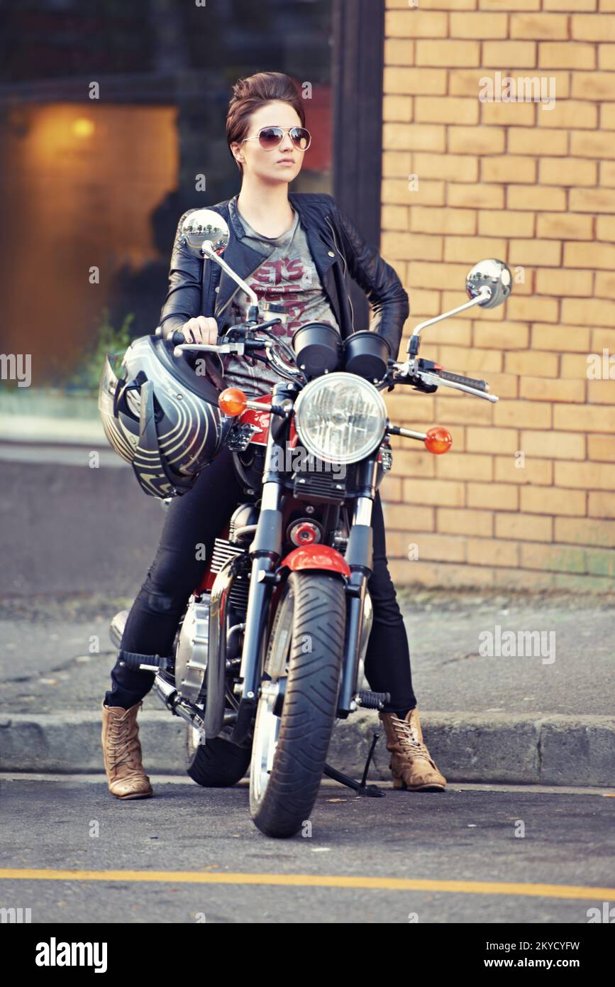 Elle fait de ce vélo un bon look. une jeune et élégante motard femme dehors. Banque D'Images