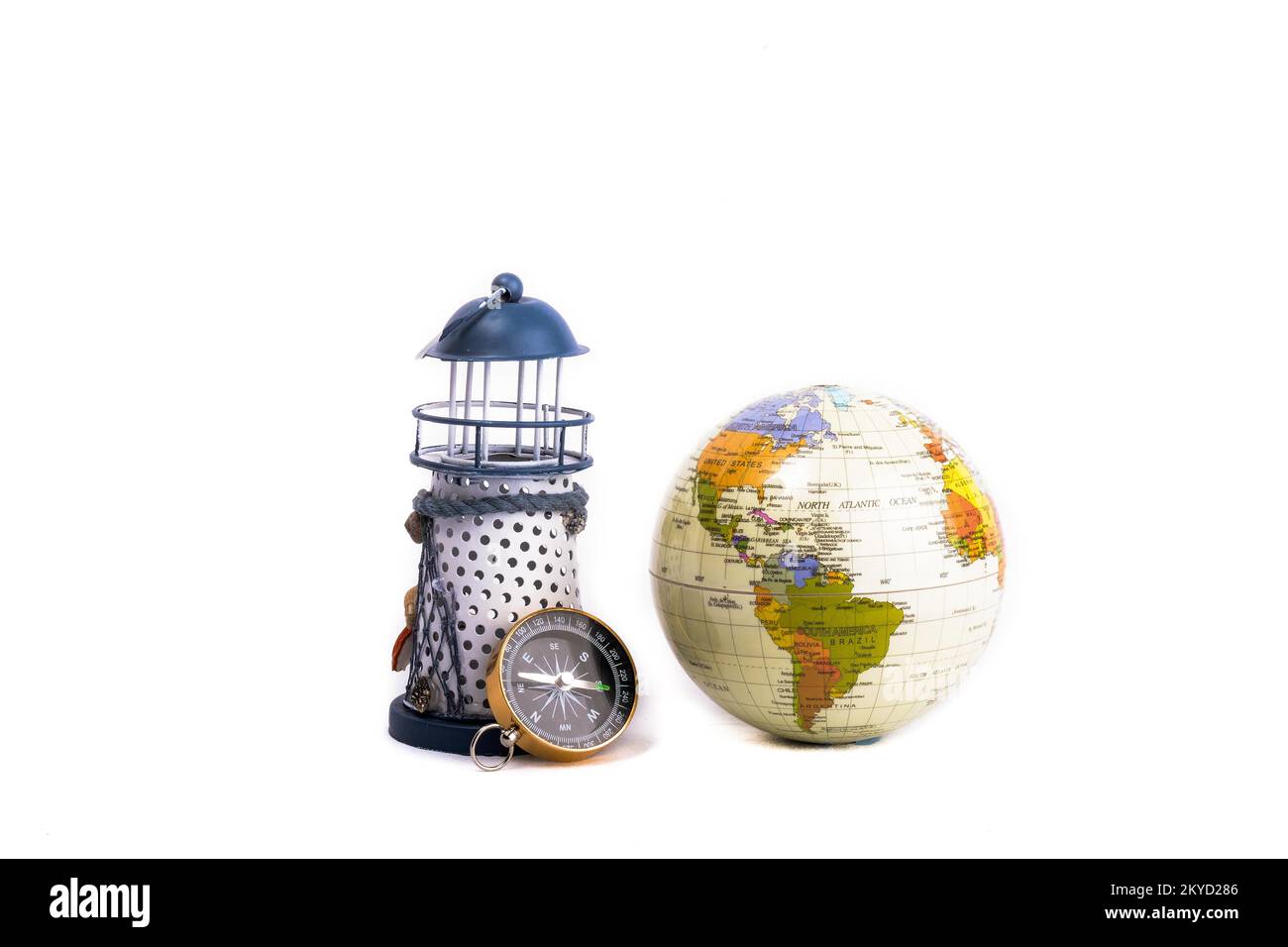 Phare, globe et boussole côte à côte sur fond blanc Banque D'Images
