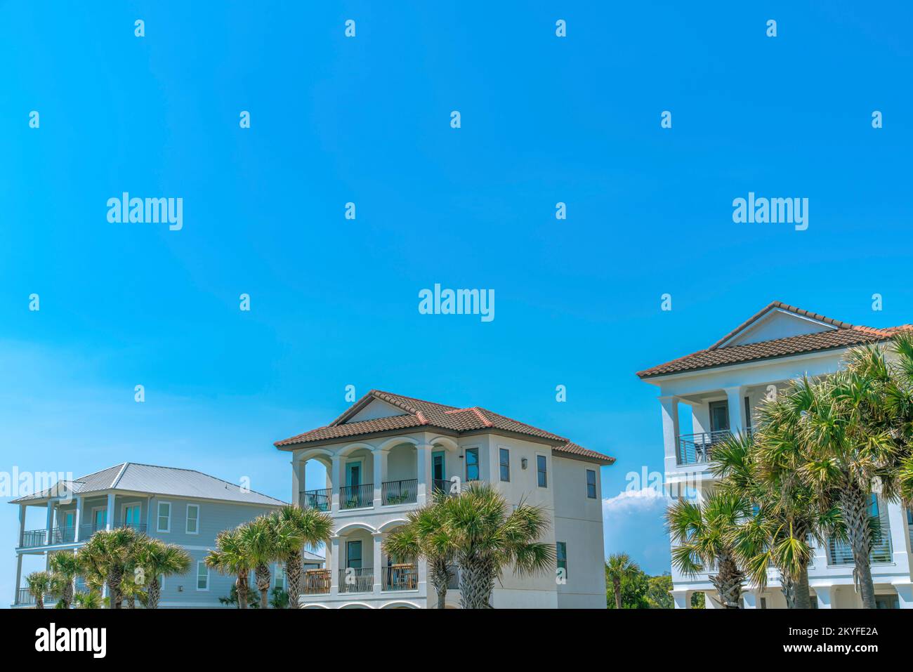 Destin, Floride - extérieur de la façade des maisons de plage contre le ciel bleu. Trois maisons de plage avec palmiers à l'avant de ses balcons. Banque D'Images