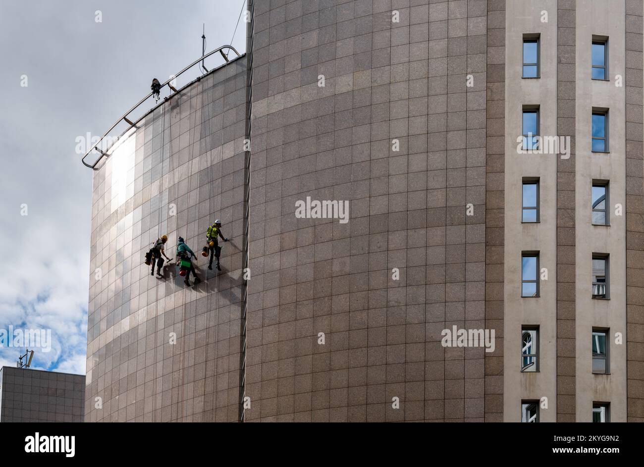 Budapest, Hongrie - 4 octobre 2022 : techniciens d'accès à la corde suspendus sur le côté d'une tour en métal et nettoyant la façade Banque D'Images