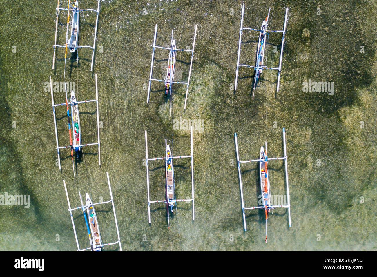 Vue de haut en bas d'un groupe de bateaux de pêche traditionnels balinais amarrés à la rive. Bateaux avec poutres supplémentaires sur les côtés contre la toile de fond de Banque D'Images