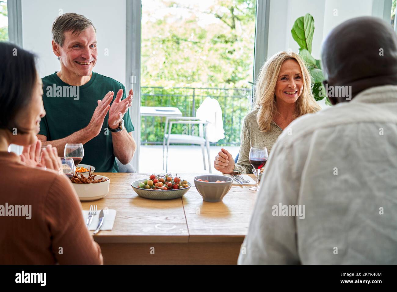 Deux couples mûrs divers se sont réunis à la table en passant un bon moment Banque D'Images