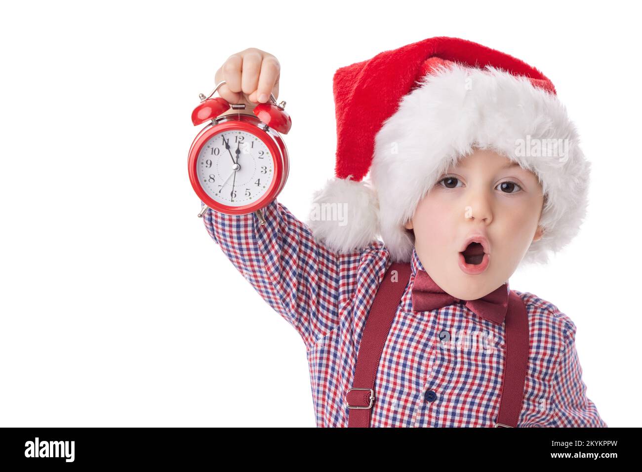 Garçon de Noël avec réveil rouge, petit homme souriant en chapeau de Père noël rouge, cravate et suspension posant sur fond blanc Banque D'Images