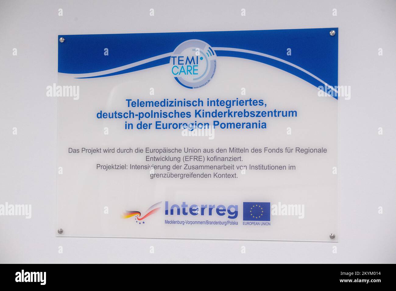 01 décembre 2022, Mecklembourg-Poméranie occidentale, Greifswald: Un panneau avec les mots «Telemedically Integrated, German-Polish Pediatric cancer Center dans l'Eurorégion Pomerania» est accroché derrière un dispositif NM/CT 870 DR de General Electric Medical Systems, Israël dans les salles de la clinique pédiatrique du centre médical de l'université Greifswald. Ce système SPECT/CT permet des examens médicaux nucléaires encore plus précis. Ceci est nécessaire pour les options de traitement spéciales telles que la thérapie par radio-isotope. La tomodensitométrie (CT) utilise un grand nombre d'images radiologiques pour calculer les images numériques. Une acquisition SPECT, sur t Banque D'Images