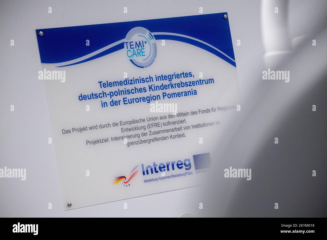 01 décembre 2022, Mecklembourg-Poméranie occidentale, Greifswald: Un panneau avec les mots «Telemedically Integrated, German-Polish Pediatric cancer Center dans l'Eurorégion Pomerania» est accroché derrière un dispositif NM/CT 870 DR de General Electric Medical Systems, Israël dans les salles de la clinique pédiatrique du centre médical de l'université Greifswald. Ce système SPECT/CT permet des examens médicaux nucléaires encore plus précis. Ceci est nécessaire pour les options de traitement spéciales telles que la thérapie par radio-isotope. La tomodensitométrie (CT) utilise un grand nombre d'images radiologiques pour calculer les images numériques. Une acquisition SPECT, sur t Banque D'Images