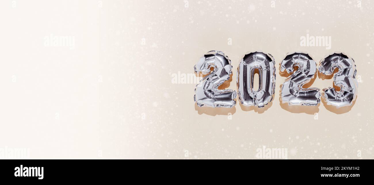 Bannière de Noël ou du nouvel an. Fond de couleur beige avec 2023 numéros de ballons brillants argentés du côté droit. Copier l'espace depuis la gauche. Neige blanche Banque D'Images