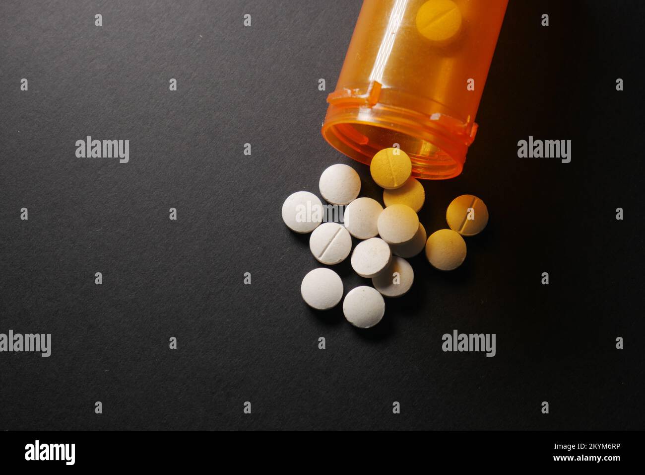 des pilules médicales de couleur blanche débordent sur fond noir Banque D'Images