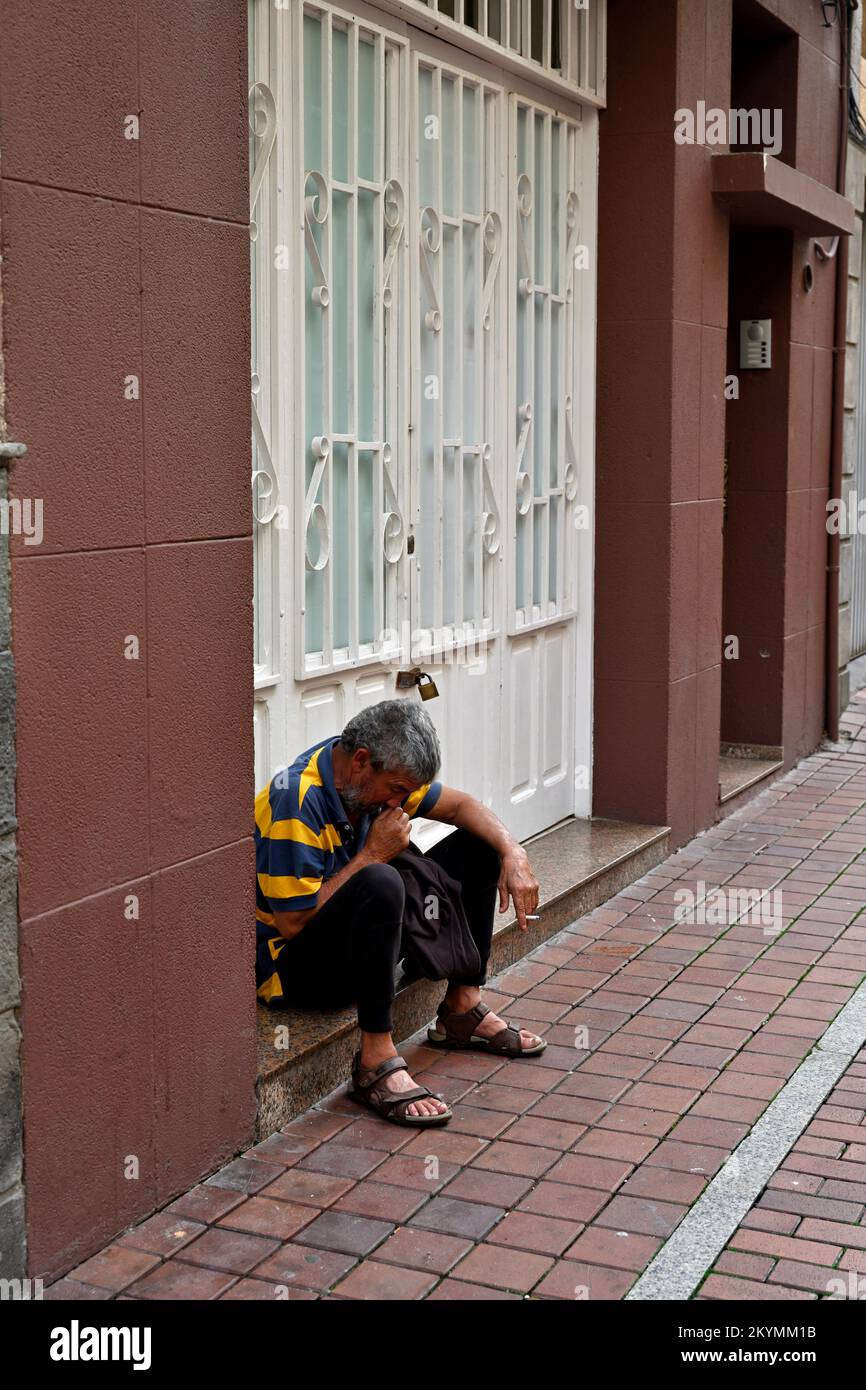Homme assis sur la marche dans la porte se détendant avec la cigarette Banque D'Images