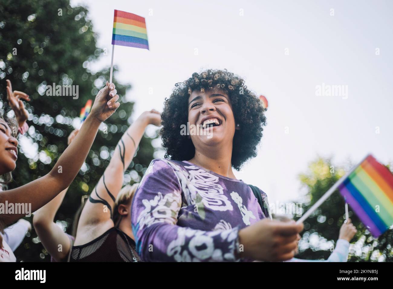 Bonne femme transgenre avec drapeau arc-en-ciel appréciant dans la parade de fierté gay Banque D'Images