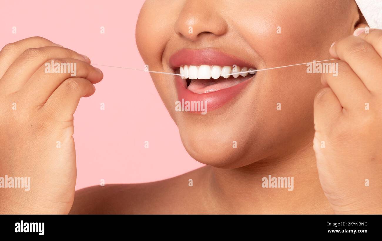 Concept de soins de la bouche et de soins de la bouche. Gros plan coupe courte d'une femme obèse noire non reconnaissable utilisant de la soie dentaire Banque D'Images
