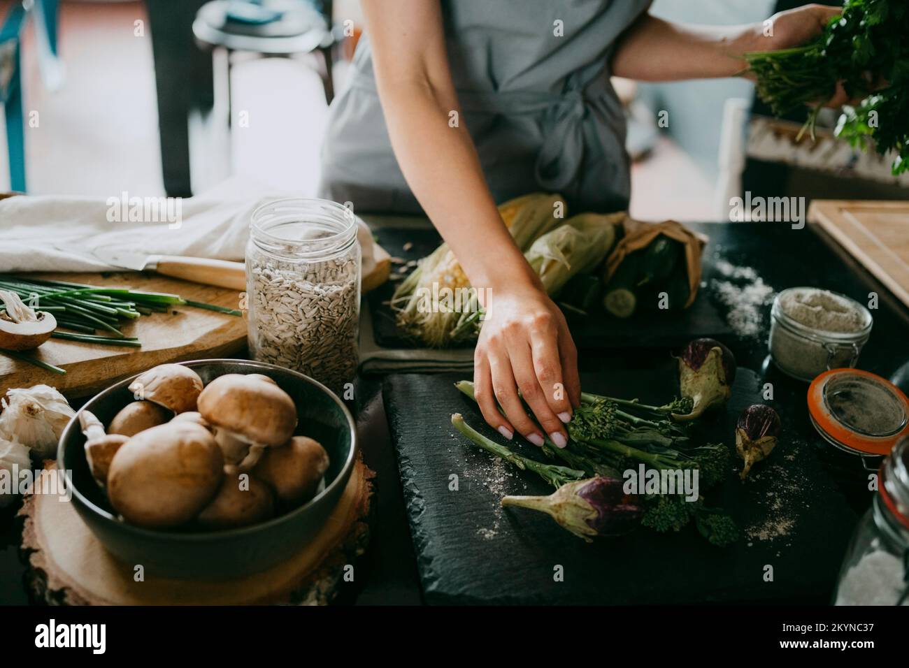 Chef féminin organisant broccolini et aubergines sur ardoise au comptoir dans la cuisine studio Banque D'Images