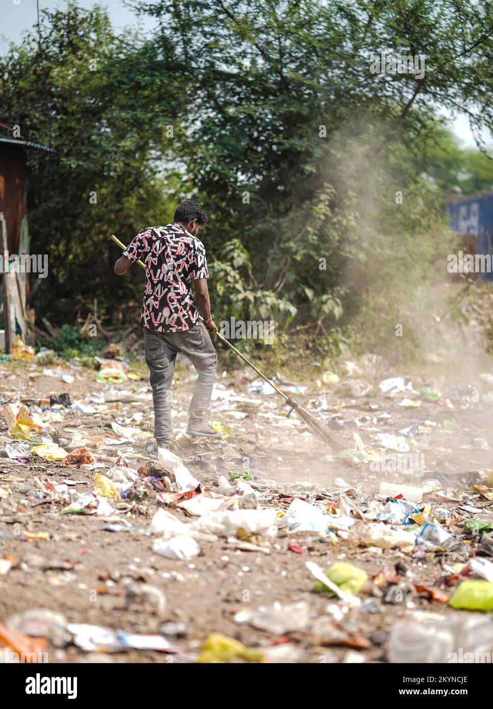 Homme balayant les ordures avec un balai et de la grande zone de déchets en polyhthène, homme nettoyant la zone polluée, journée de contrôle de la pollution, concept de pollution Banque D'Images