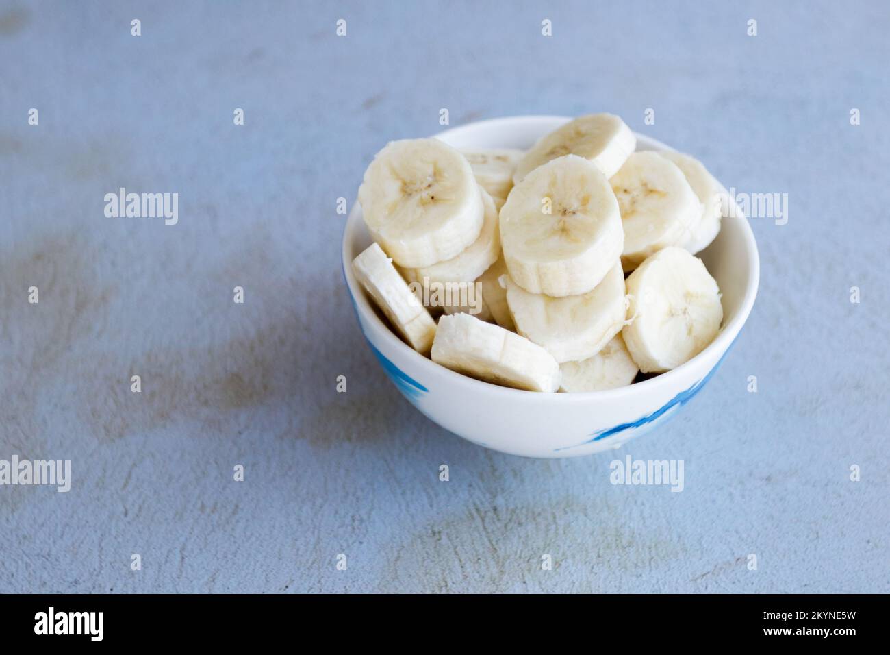 Bol rempli de tranches de banane sur un fond abstrait. Concept de nourriture saine, fruits. Banque D'Images