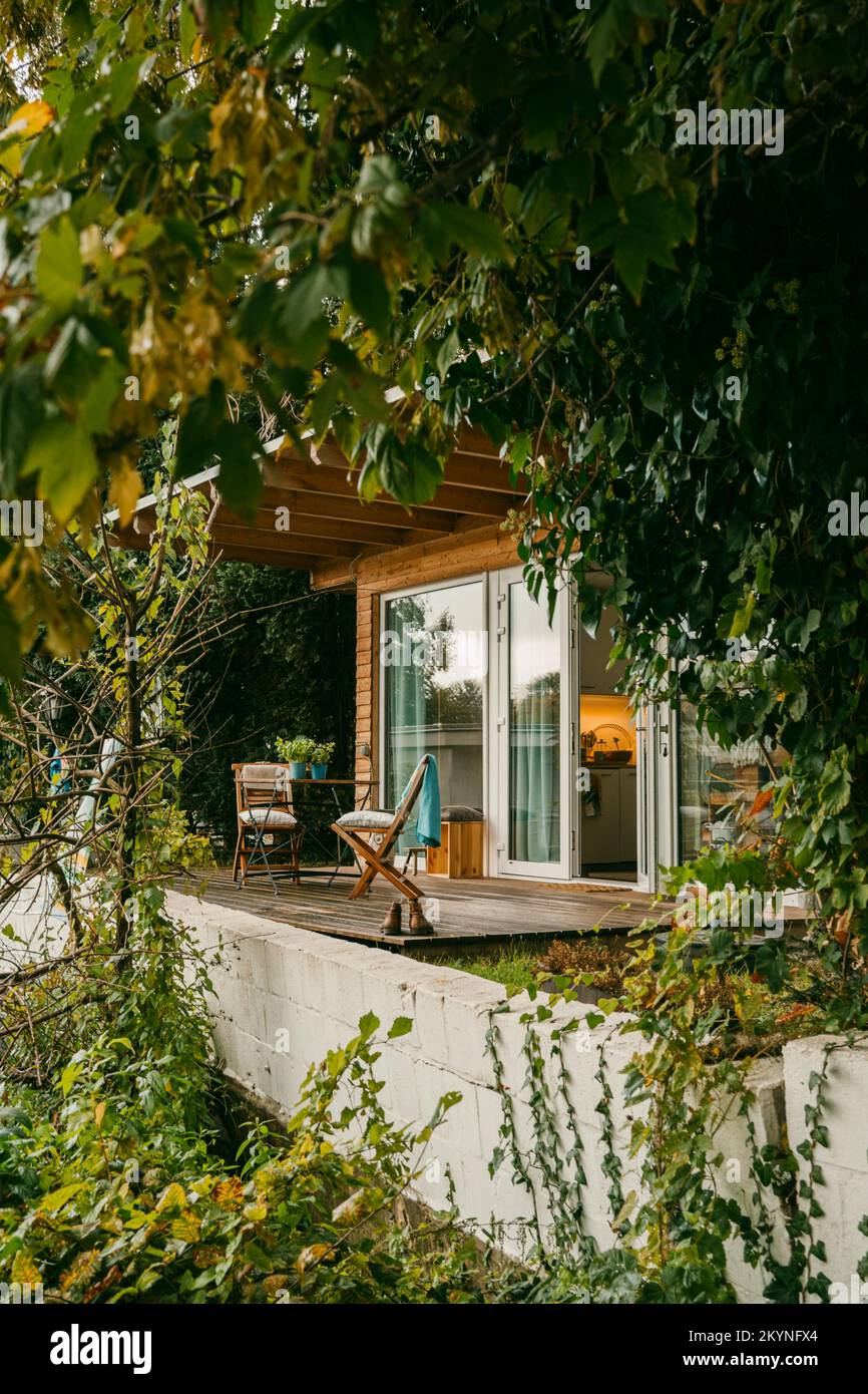 Chaises sur porche en bois au milieu des plantes à l'extérieur de la maison Banque D'Images