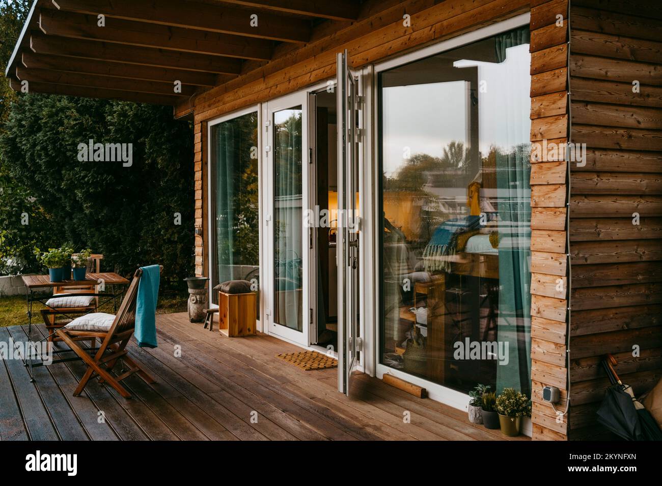 Porche en bois avec chaises par porte en verre à l'extérieur de la maison Banque D'Images