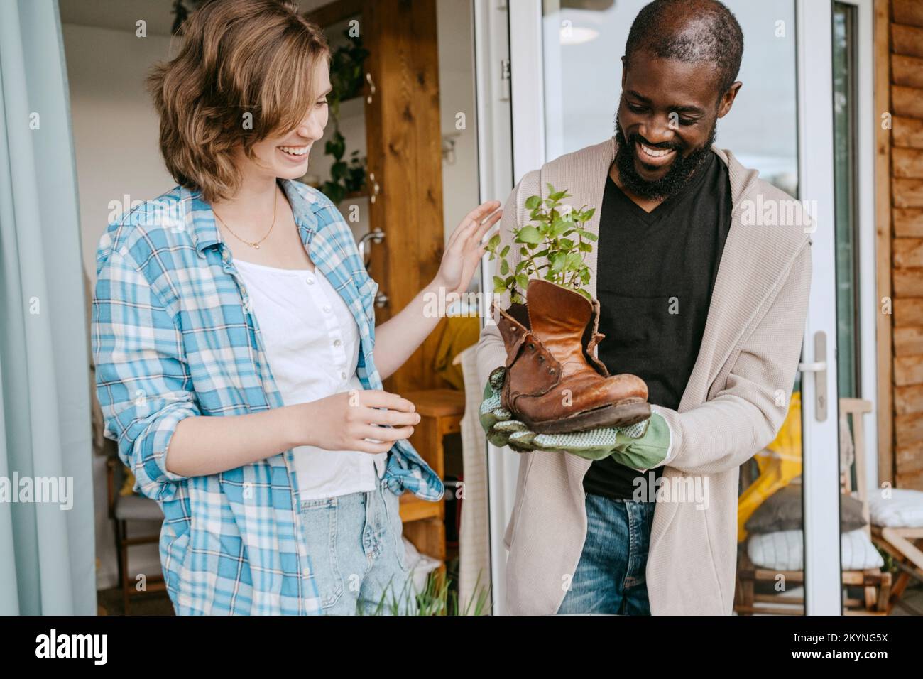 Heureux homme mature montrant plante en cuir bottes à la femme tout en se tenant sur le porche Banque D'Images