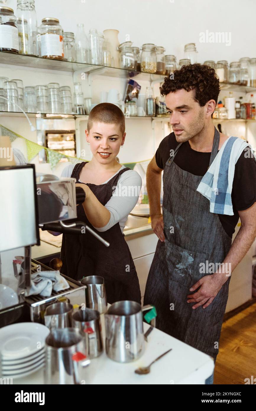 Les propriétaires de sexe féminin et masculin apprennent à utiliser la cafetière au café Banque D'Images