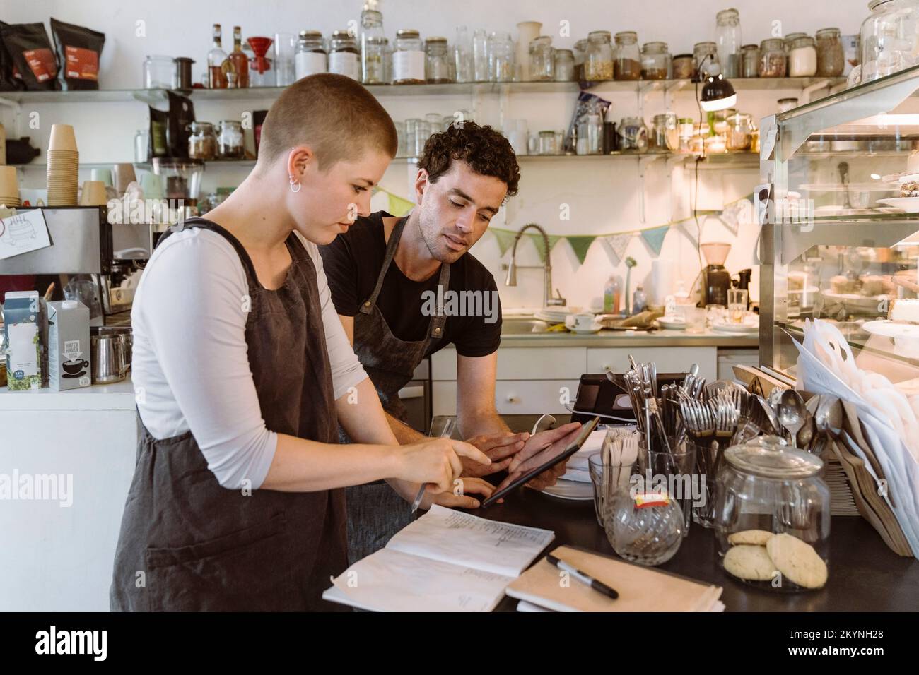 Les propriétaires de sexe masculin et féminin font l'inventaire en utilisant un Tablet PC au café Banque D'Images